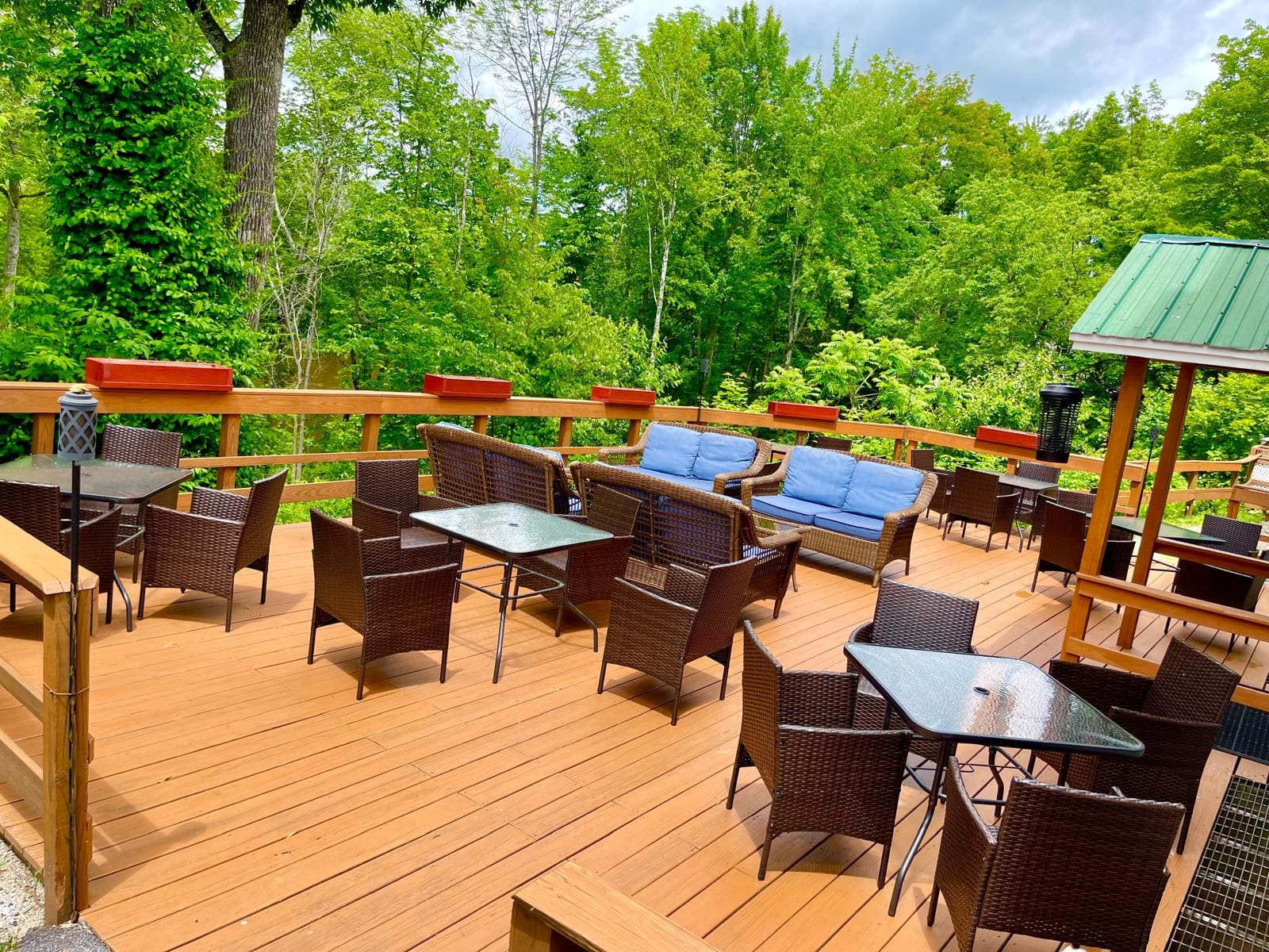 Outdoor dining tables on the wooden deck surrounded by trees at Merrill Farm Inn